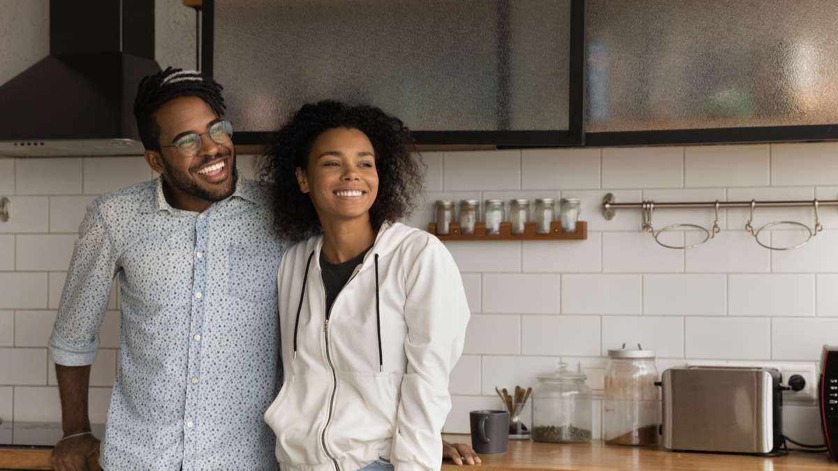 Happy African couple standing in kitchen smile looking into distance (R) (S)
