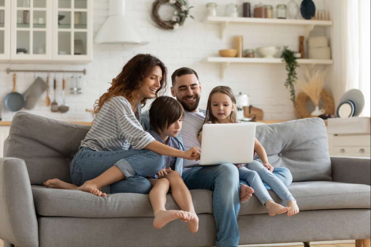 Happy young family with little kids sit on sofa in kitchen (R) (S)