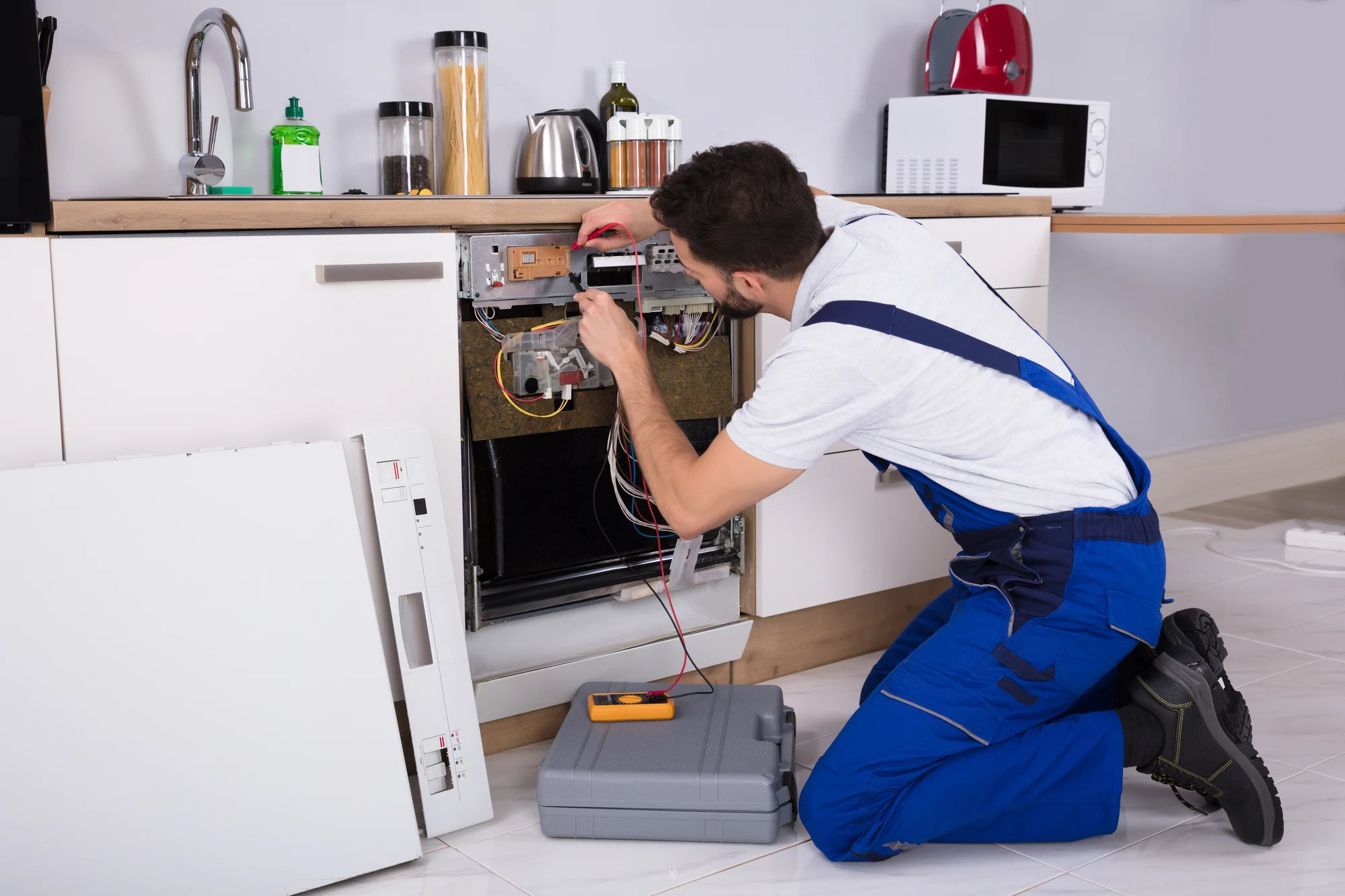 Male Technician Examining Dishwasher With Digital Multimeter